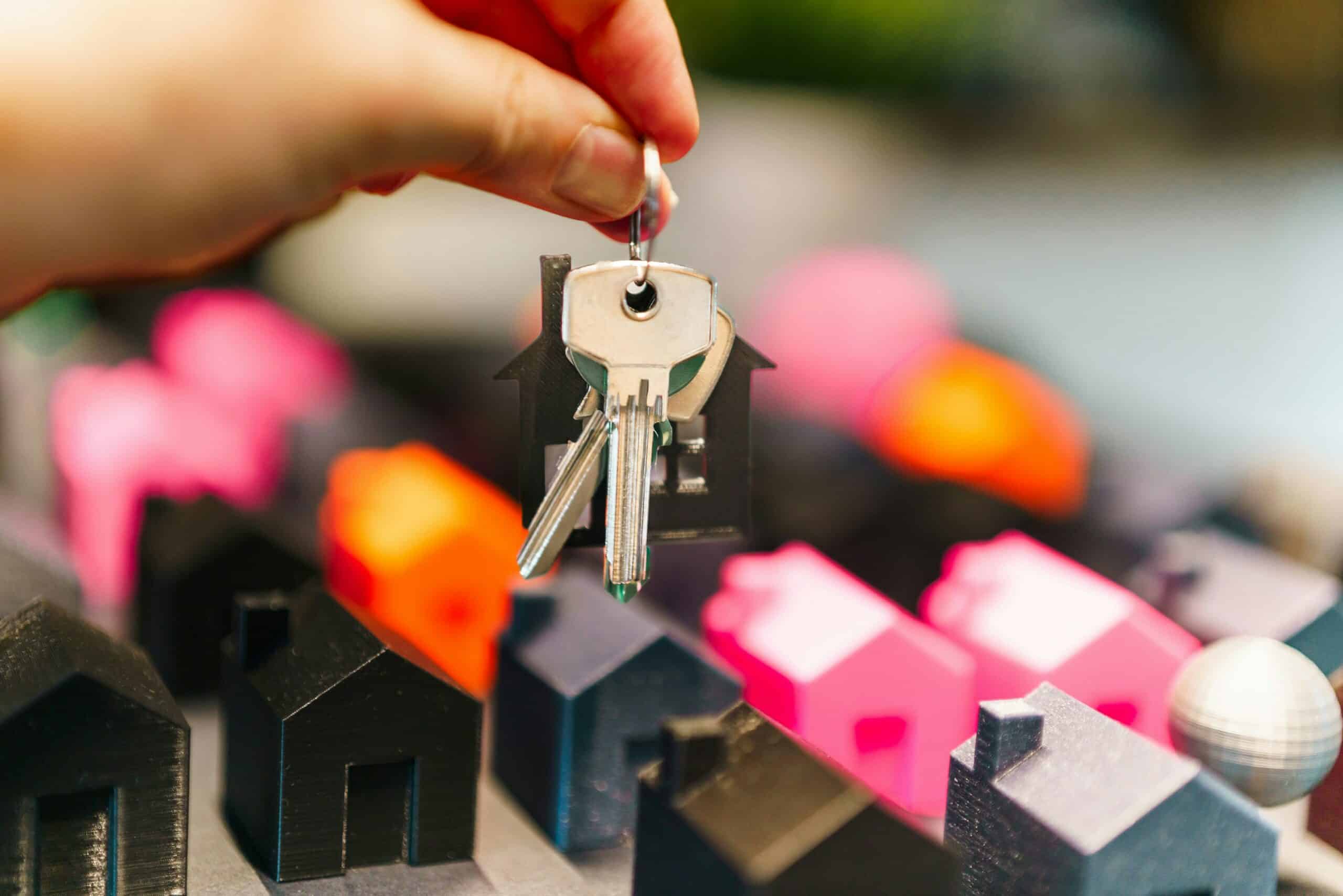 House keys held above model homes representing buy to let mortgage advice